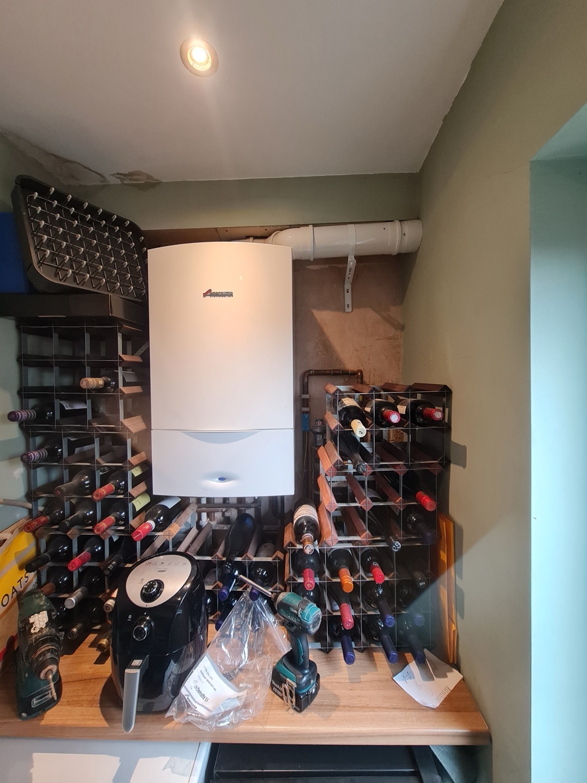 A wall-hung boiler fitted into the sort of awkward cupboard most houses actually have — flue routed out and the cupboard still usable.